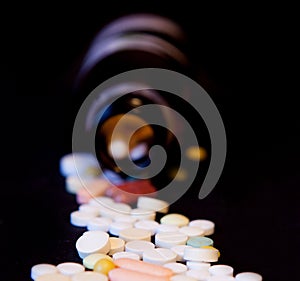 A bottle of spilled pills on black background.Levitating tablets. Tablets on a dark background that are falling. Tablets. Medicine