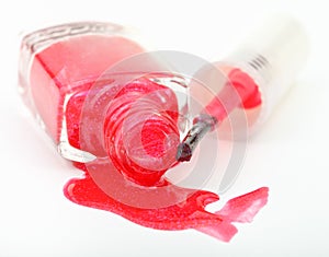 Bottle with spilled red nail polish on white
