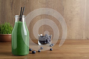 Bottle of spirulina smoothie with berries on table