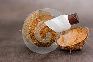 Bottle sticks out in a coconut shell on gray background. Fresh organic coconut milk. Delicious substitution for lactose intolerant photo