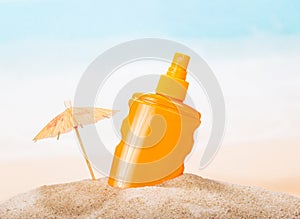 Bottle of sunscreen in the sand against sea.