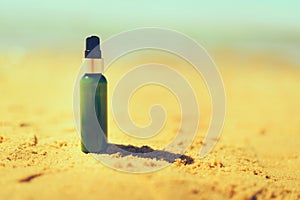 Bottle of sunscreen in sand against sea background with copyspace. Vacation and travel wallpaper. Skin care concept.