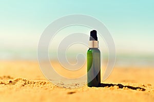 Bottle of sunscreen in sand against sea background with copyspace. Vacation and travel wallpaper. Skin care concept.