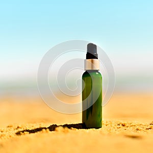 Bottle of sunscreen in sand against sea background with copyspace. Vacation and travel wallpaper. Skin care concept