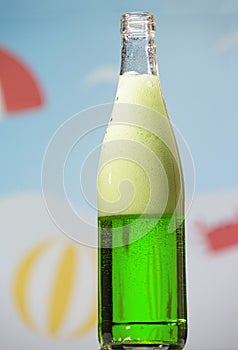 Bottle with tarragon carbonated drink on summer background