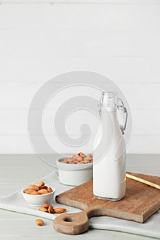Bottle of tasty almond milk on color wooden table