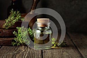 Bottle of thyme essential oil with fresh thyme twigs