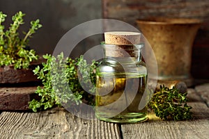 Bottle of thyme essential oil with fresh thyme twigs