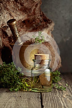 Bottle of thyme essential oil with fresh thyme twigs