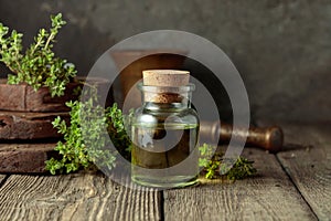 Bottle of thyme essential oil with fresh thyme twigs
