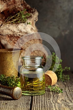 Bottle of thyme essential oil with fresh thyme twigs