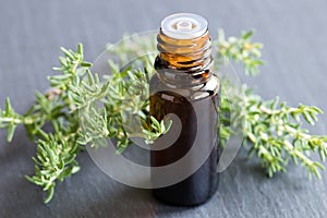 A bottle of thyme essential oil with fresh thyme twigs