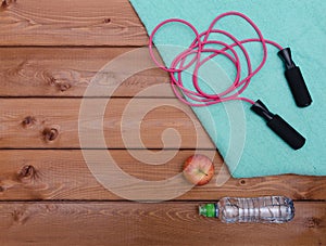 Bottle with towel water and skipping rope on wooden table