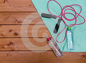 Bottle with towel water and skipping rope on wooden table