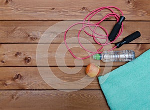 Bottle with towel water and skipping rope on wooden table background.