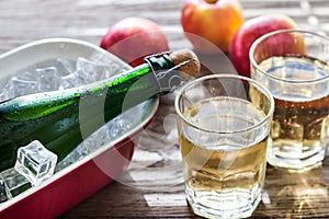 Bottle and two glasses of cider on the wooden background