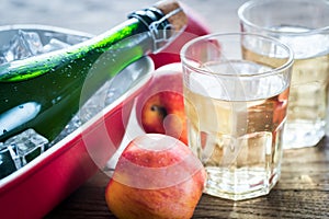 Bottle and two glasses of cider on the wooden background