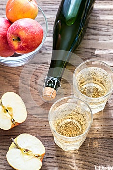 Bottle and two glasses of cider on the wooden background