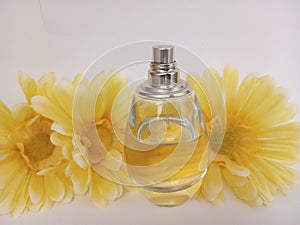 A bottle of unisex perfume with yellow daisies on a white background