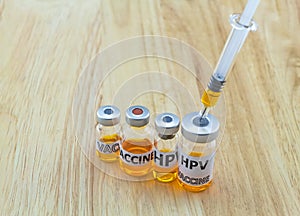 Bottle vaccine of Human papillomavirus (HPV) vaccine and disposable syringe on wooden background