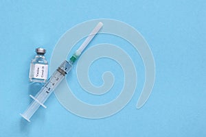 Bottle with vaccine and medicine syringe with vaccine on blue background. Concept of vaccination and healthcare