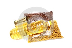 A bottle of vegetable oil, buckwheat, pasta in plastic bags and canned food, isolated on a white background