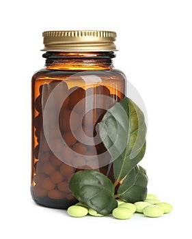 Bottle with vitamin pills and green leaves on white