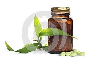 Bottle with vitamin pills and green leaves on white