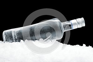 Bottle of vodka lying on ice on black background