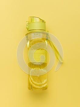 A bottle of water and lemon for training on a yellow background