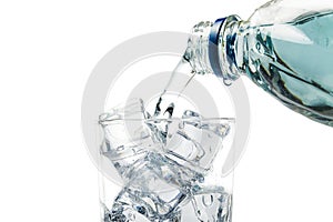 From the bottle water pours into a glass of ice, on a white background