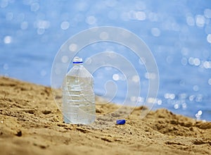 Bottle with water on the sandy coast