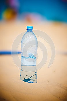 Bottle of water standing in sand at the beach