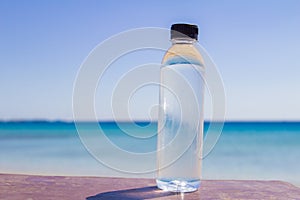 A bottle of water on a table on the beach on a sunny day as a symbol of proper nutrition