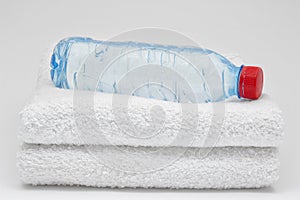 Bottle of water and towels. On grey background