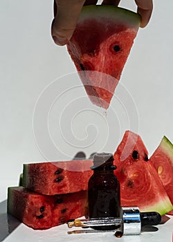 A bottle of watermelon seed oil. Packaging of natural essential oil or serum for the face with watermelon on a white background.