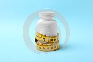 Bottle of weight loss pills with measuring tape