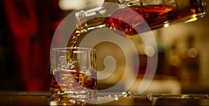 A bottle of whiskey being poured into a glass with ice