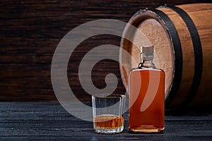 Bottle of whiskey on a black wooden in oak barrels