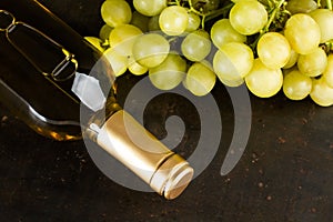 A bottle of white wine anda a bunch of white grapes