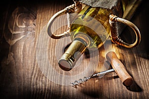 Bottle of white wine in burlap bag and vintage corckscrew