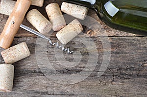 Bottle of white wine, corkscrew and corks on wooden table.