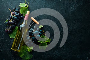 Bottle of white wine and fresh grapes on a black stone table. Top view.