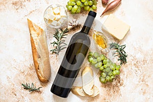 A bottle of white wine, grapes, cheese, butter, honey, baguette, shallot and rosemary