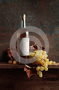 Bottle of white wine with grapes and dried up vine leaves