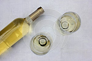 A bottle of white wine and two glasses on white background. Summer celebration in the garden. Selective focus. Copy space