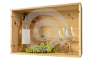 A bottle of white wine, two wine glasses and white grapes in a wooden box from wine bottles