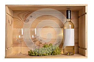 A bottle of white wine, two wine glasses and white grapes in a wooden box from wine bottles