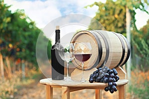 Bottle of wine, barrel and glasses on wooden table