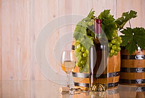 Bottle of wine with barrels grapes and grapeleaves